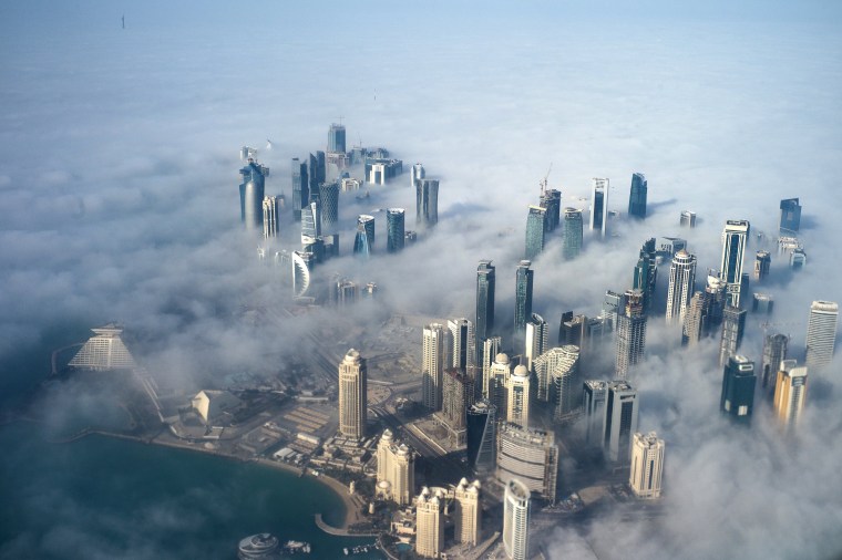 Image: An aerial view of high-rise buildings emerging through fog covering the skyline of Doha.