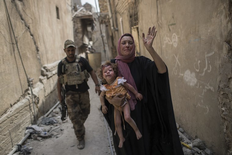 Image: A woman holds a young injured girl in the Old City of Mosul