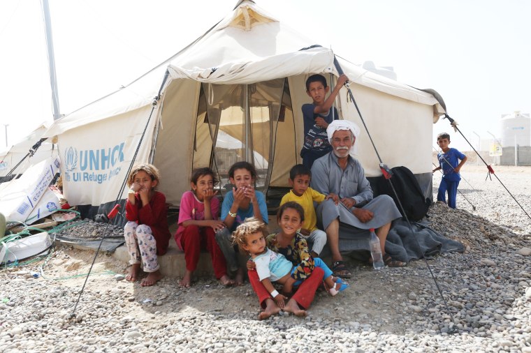 Image: Saleh Saleh sits with his family outside a tent at the Hammam al-Alil refugee camp in northern Iraq