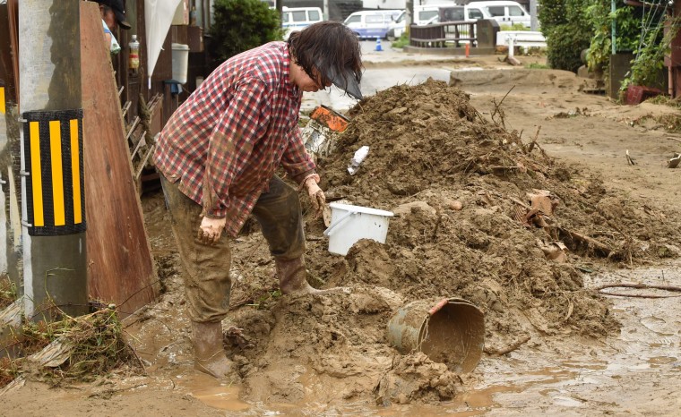 Image: A woman removes mud from her house following heavy flooding in Asakura