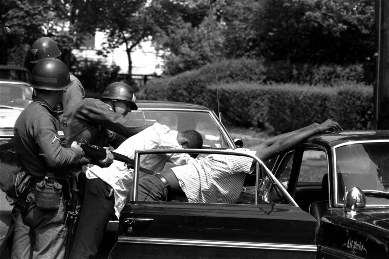 Image: Men are searched at a bayonet point by National Guardsmen