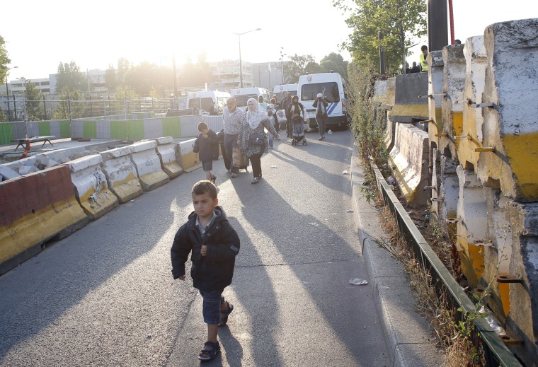 Image: Migrants walk towards buses