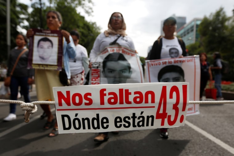 Image: A banner is seen as relatives hold posters with images of some of the 43 missing Ayotzinapa College Raul Isidro Burgos students during a march to mark the 33rd month since their disappearance, in the state of Guerrero, in Mexico City