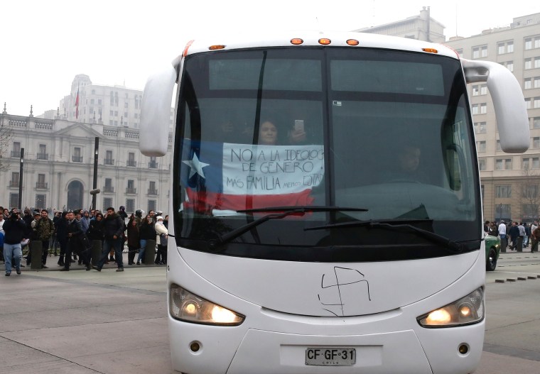 Image: A woman holds a national flag with the words "No to transgender ideology, more family, less state" while riding on a bus of conservative advocacy group Citizen Go in Santiago