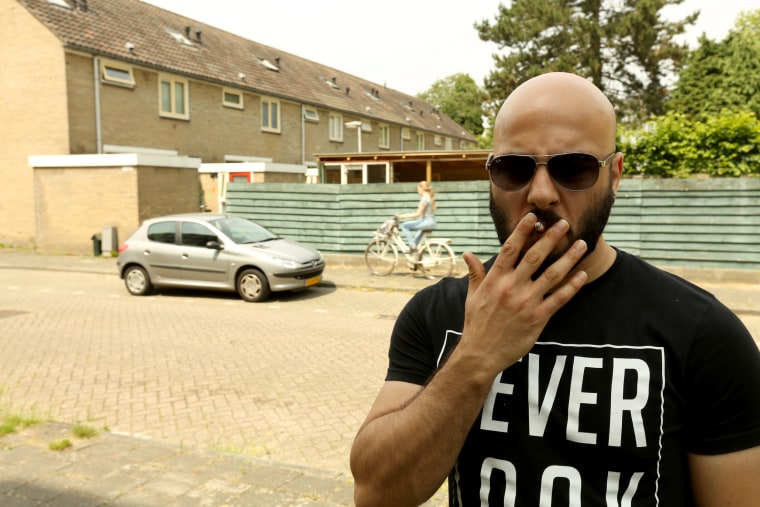 Image: Saflou smokes a cigarette outside his new apartment