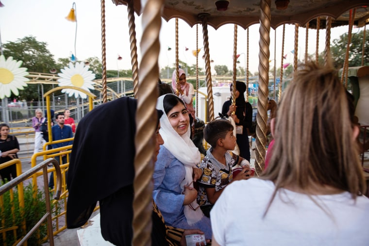 Image: Malala Yousafzai visits an amusement park and rides a carousel with children displaced by ISIS conflict