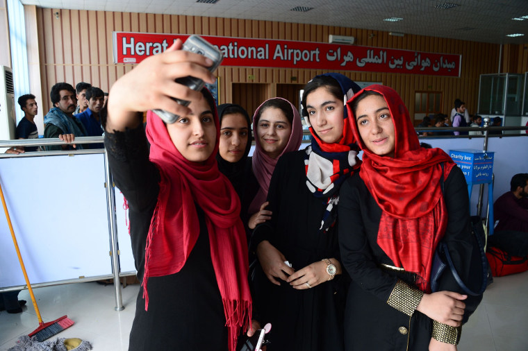 Image: Afghan teenagers from the Afghanistan Robotic House take pictures with a mobile phone at Herat International Airport, before embarking for the United States