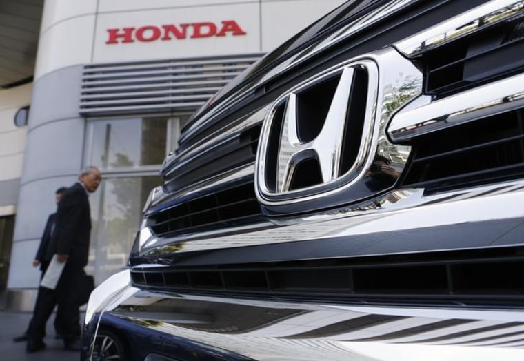 Visitors look at a Honda Motor Co's car displayed outside the company showroom in Tokyo