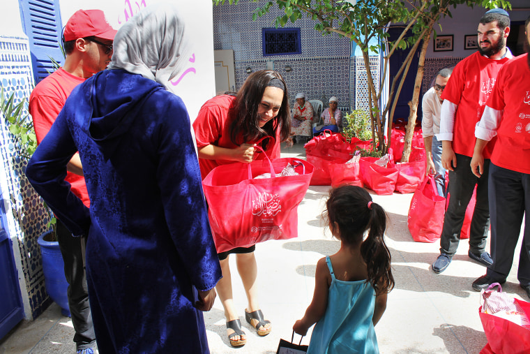 Image: A woman hands a child a bag of food