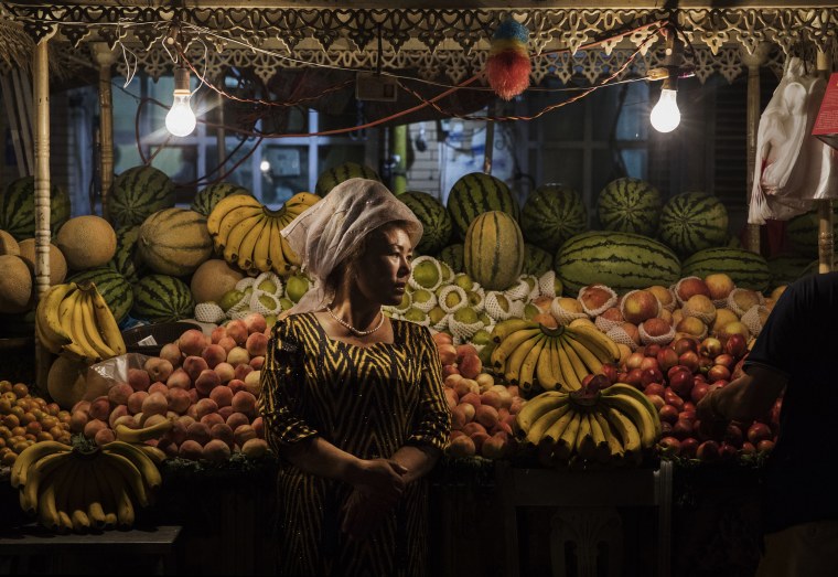 Image: An ethnic Uyghur woman waits for customers at her fruit stand