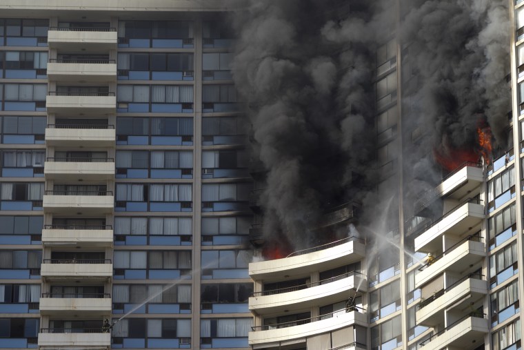 Firefighters on several balconies spray water upwards while trying to contain a fire at the Marco Polo apartment complex, Friday, July 14, 2017, in Honolulu.