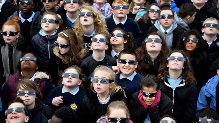 Kids looking through special glasses to view a solar eclipse.