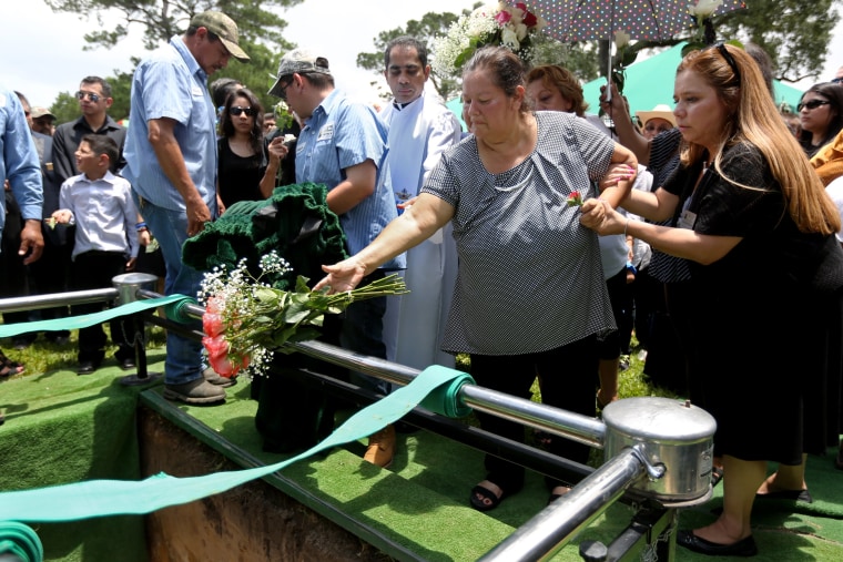 Maria Flores tosses flowers into the grave of her son Josue Flores