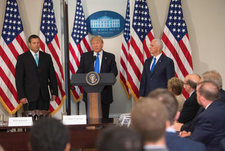 Image: President Donald Trump speaks alongside Kansas Secretary of State Kris Kobach, left, and Vice President Mike Pence