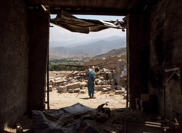 Image: A boy walks through damaged buildings