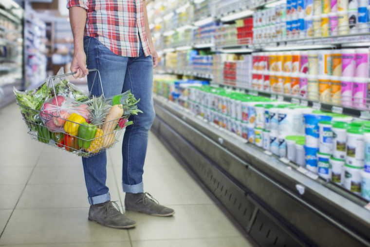 Image: A man carries a shopping basket in a grocery store