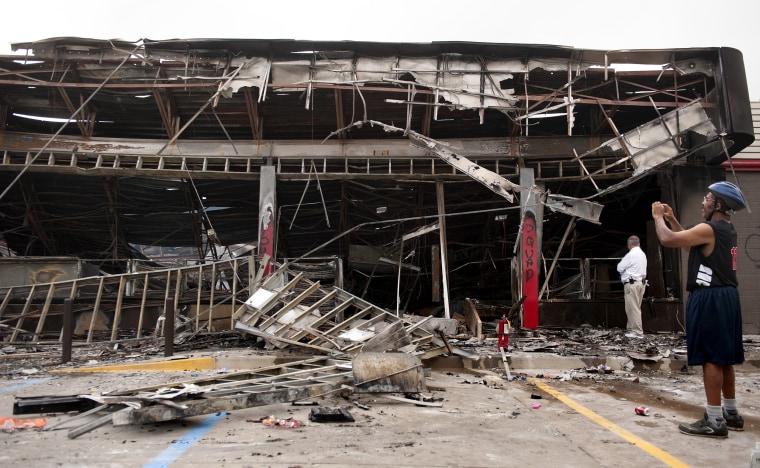 Image: People look at the burned QuikTrip gas station