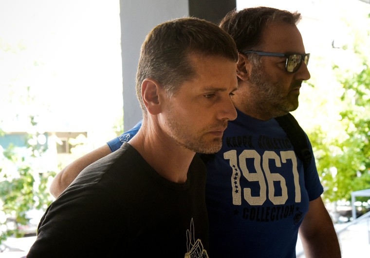 Image: Alexander Vinnik, a Russian man suspected of running a money laundering operation, is escorted by a plain-clothes police officer to a court in Thessaloniki