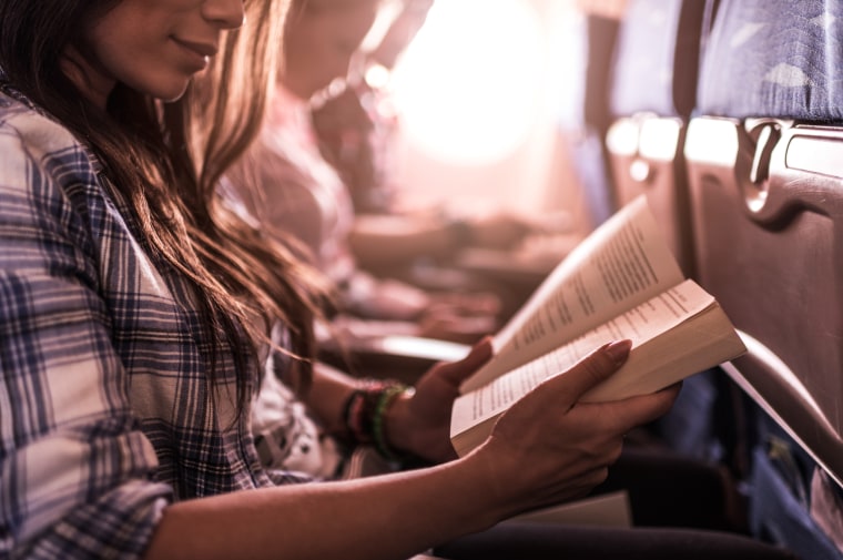 Image: A woman reads a book on the plane