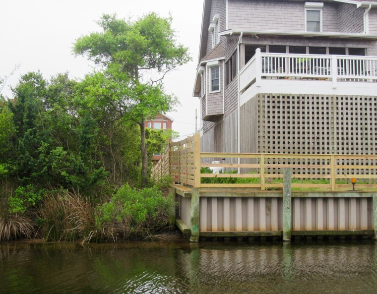 A bulkhead constructed directly adjacent to a natural marsh shoreline in Frisco, NC