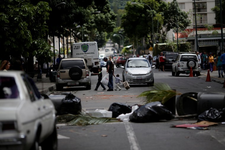 Image: People walk through a barricade after a strike called to protest against Venezuelan President Nicolas Maduro's government in Caracas