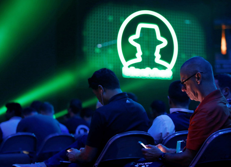 Image: Attendee Don Laursen checks the conference schedule on his phone as he waits for a keynote address during the Black Hat information security conference in Las Vegas