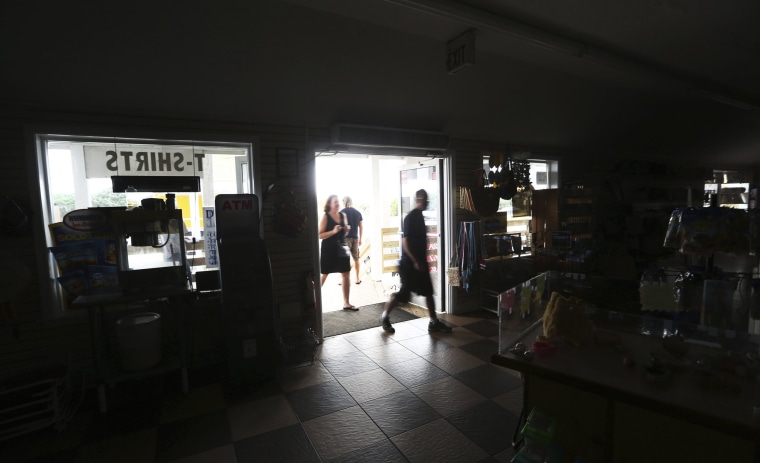 Image: Customers enter the darkened Island Convenience Store