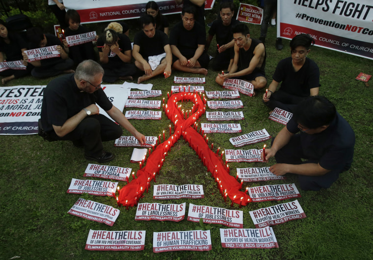 A priest lights candles around an AIDS symbol as he participates in an event in observance of World AIDS Day in Quezon city, Philippines.