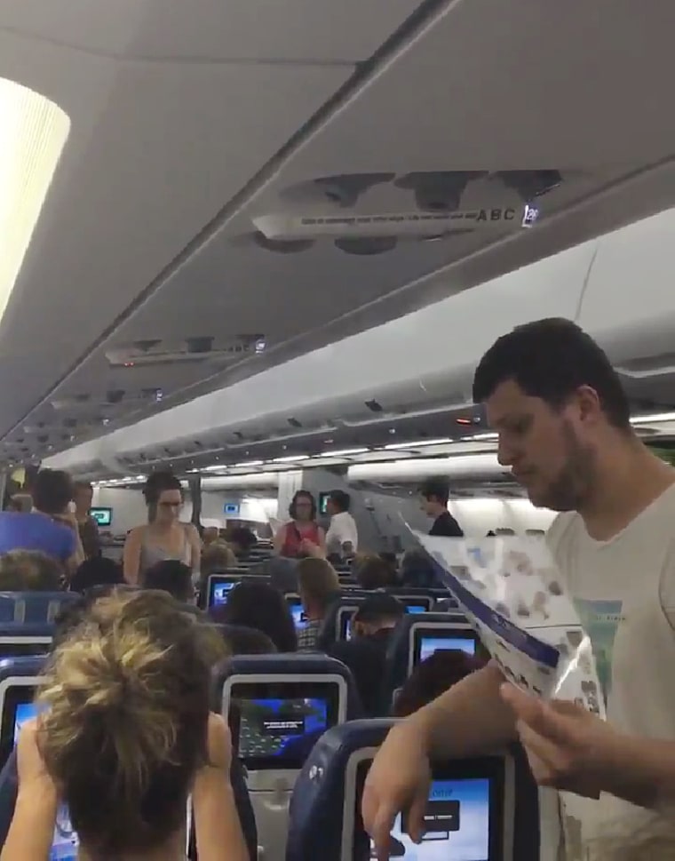 Passengers fan themselves as medical staff come on board the Air Transat plane that was on a tarmac in Ottowa, Canada for over 5 hours.