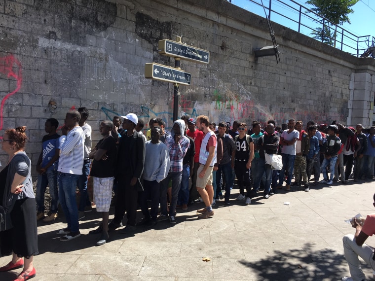 Image: Migrants line up for breakfast distributed by volunteers in Porte de la Chapelle, Paris.