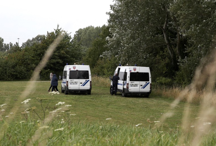 Image: Police vans near woodland where migrant families are sheltering at Grande Synthe, Dunkirk, northern France.