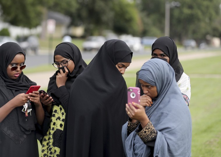 Image: People make phone calls as law enforcement investigate an explosion at the Dar Al-Farooq Islamic Center