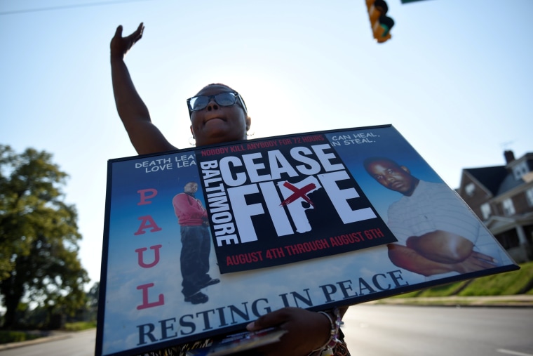 Image: A relative of a gun violence victim holds a sign at the \"Stop the Violence\" rally in Baltimore