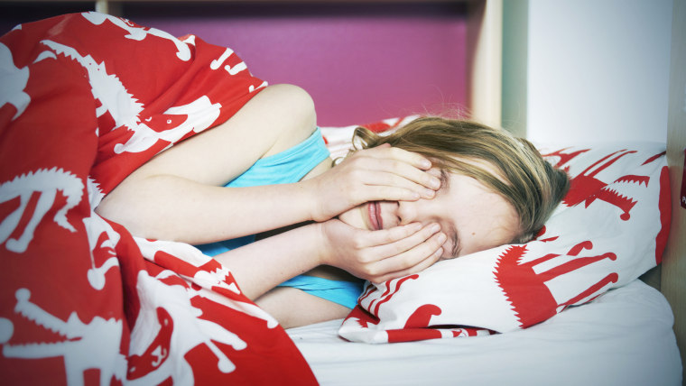 young girl rubbing eyes in bed