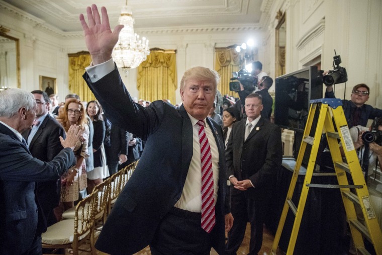 Image: Trump waves as he departs an event in the East Room at the White House