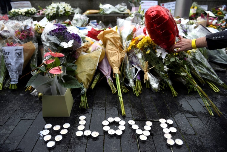 Image: A person lays a floral tribute after a vigil