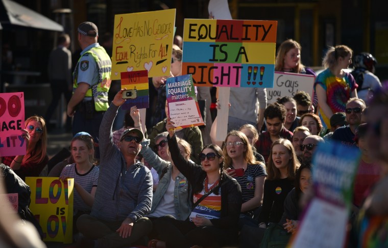 Image: Supporters of same sex marriage carry banners and shout slogans as they gather on a street in Sydney on August 6, 2017.