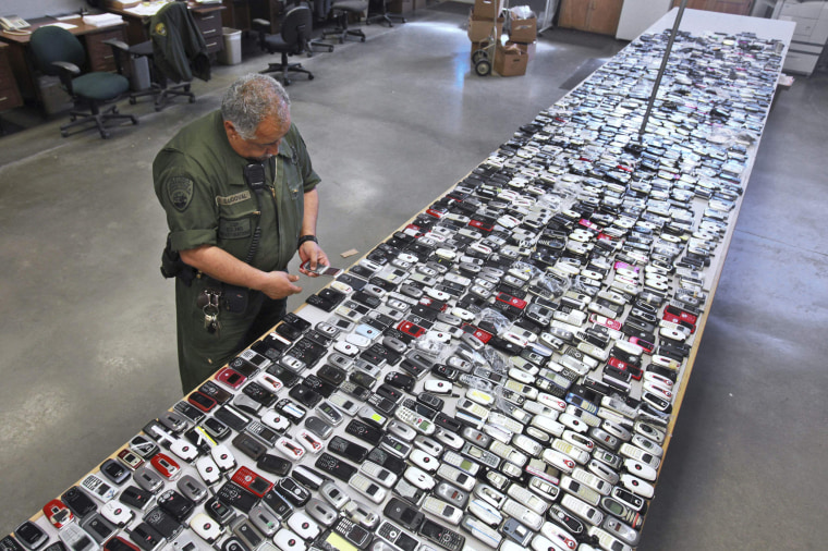 Image: A correctional officer inspects one of the more than 2,000 cell phones confiscated from inmates at California State Prison,