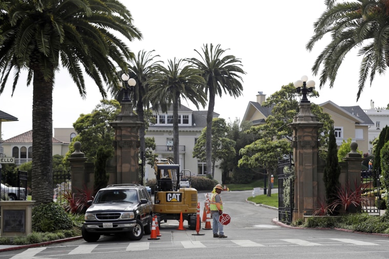 Image: A construction workers stands in front of a gate leading into the Presidio Terrace neighborhood