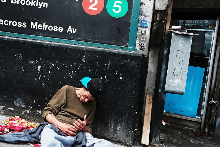 Image: A man rests against a wall appearing to be under the influence of drugs on a street in the South Bronx