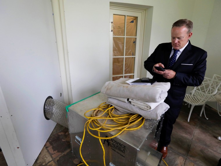 Image: Spicer checks his email outside the empty Oval Office during renovations at the White House in Washington