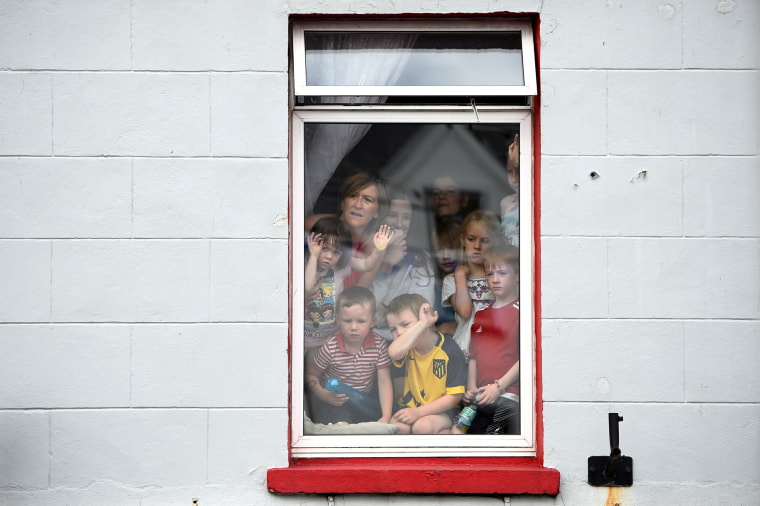 Image: People crowd into a window to see a wild goat paraded through the town before being crowned King Puck for three days in Killorglin