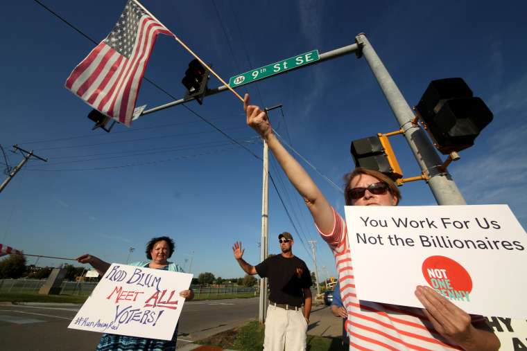 Image: Deb Rasmussen of Independence, Iowa, foreground protests with Laura Wright and Jacob Krapfl outside an Iowa Tea Party event for U.S. Rep. Rod Blum in Dyersville, Iowa, Aug. 10, 2017.