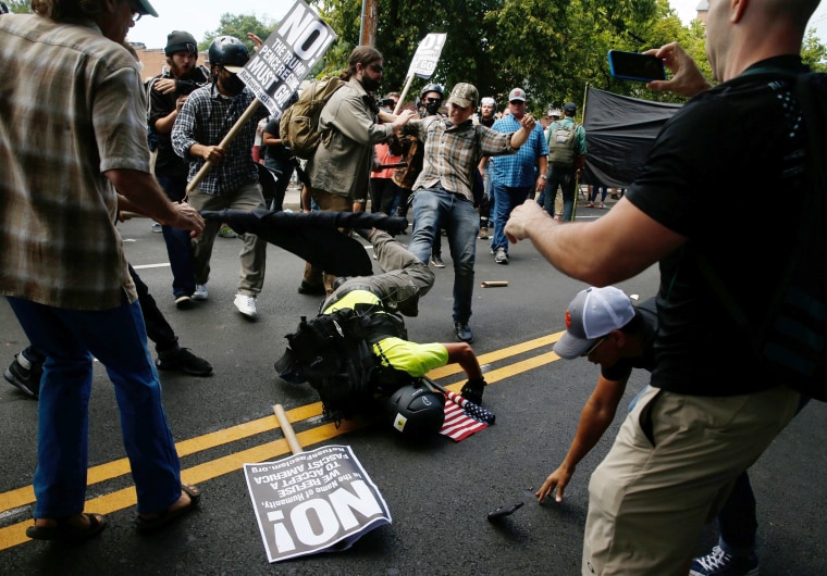 Image: A man hits the pavement during a clash between members of white nationalist protesters against a group of counter-protesters in Charlottesville