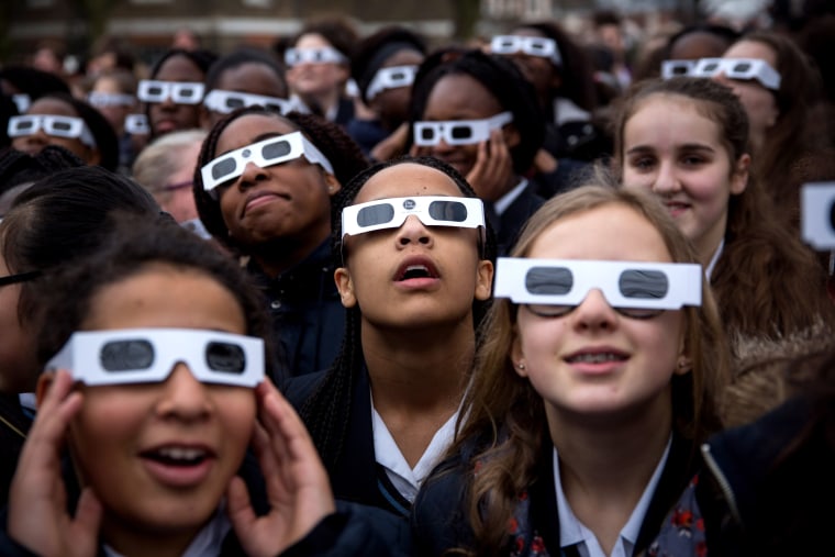 Image: Students wear protective glasses as they view a partial solar eclipse