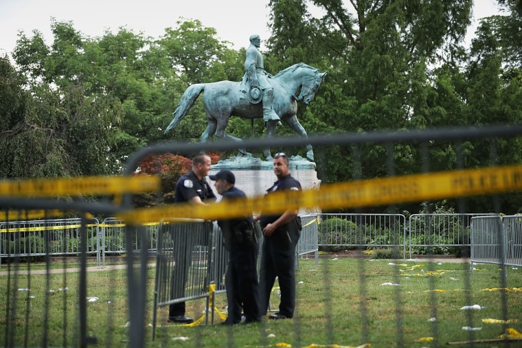 Image:  Police stand watch near the statue of Confederate Gen. Robert E. Lee in the center of Emancipation Park