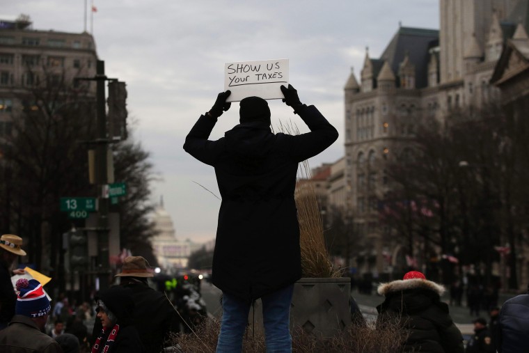 Image: A person holds up a sign in protest before the presidential inauguration of Donald Trump
