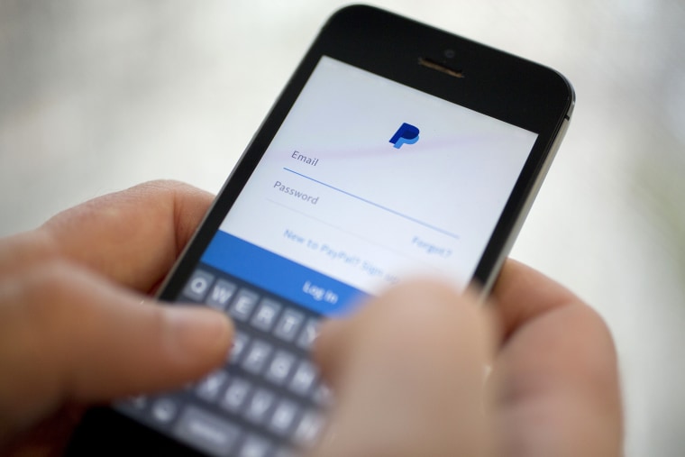 Image: A man holds a phone with the PayPal application on a mobile phone.