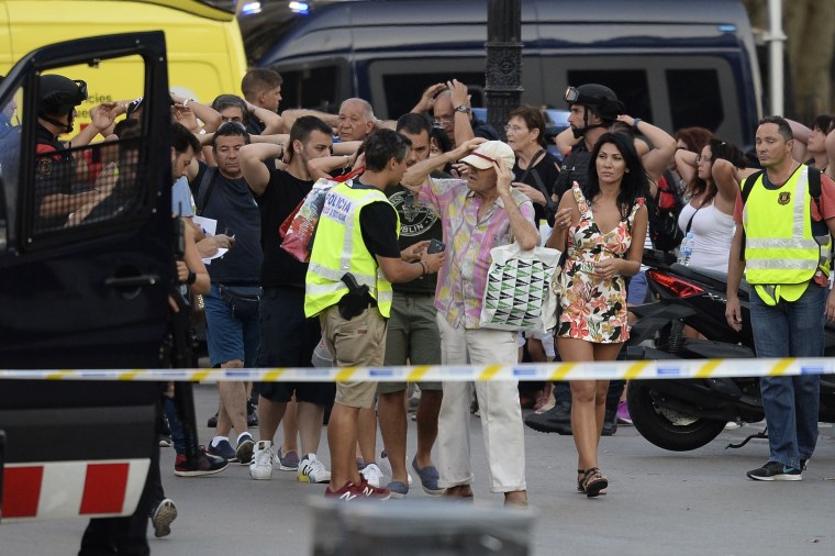 Image: Policemen check the identity of people standing with their hands up after a van struck pedestrians, killing at least 13 people