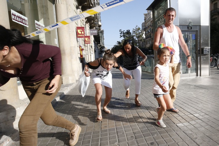 Image: People leave a cordoned off area after a van plowed through a crowded pedestrian plaza in Barcelona